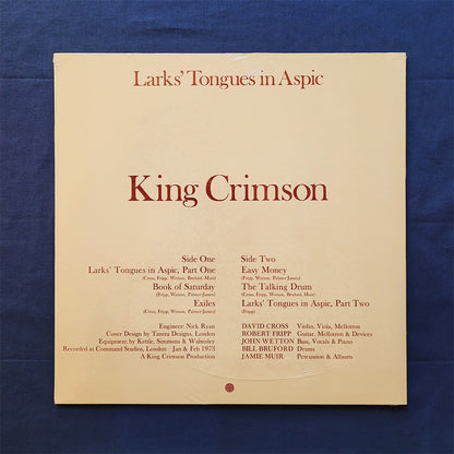 Back of King Crimson 'Larks' Tongues in Aspic' vinyl record album cover, displayed flat against a textured dark blue background.