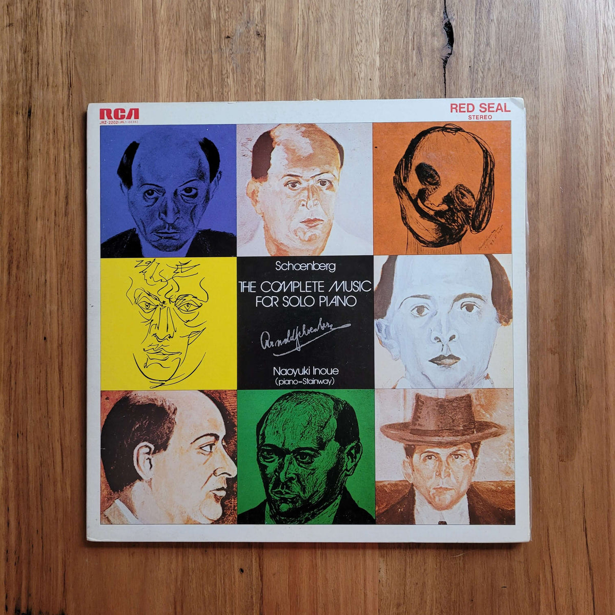 A square album cover for 'Schoenberg: The Complete Music for Solo Piano' by Nadual Fouse, released by RCA Red Seal, displayed flat on a wooden surface. The cover features a 3x3 grid of colorful portrait illustrations in blue, orange, yellow, green, black, and white.