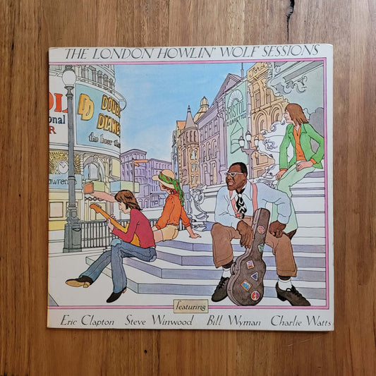 The London Howlin' Wolf Sessions vinyl record album cover by Eric Clapton, Steve Warneke, Bill Wyman, and Charlie Watts, displayed flat on a wooden floor.