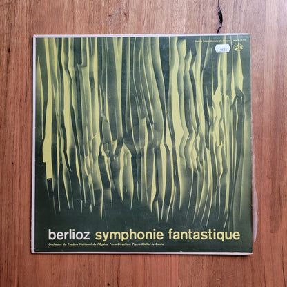 A vinyl record sleeve for Berlioz's 'Symphonie fantastique' lies on a wooden tabletop. The sleeve features an abstract green and yellow striped design with the title in white text at the bottom.