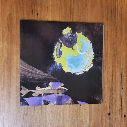 Yes - Fragile album cover art with colorful collage design on a wooden surface.
